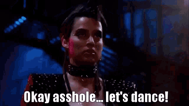 a woman is holding her arms up in the air and says `` okay asshole ... let 's dance ! ``