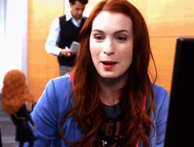 a woman with red hair is looking at a computer screen and wearing a t-shirt that says gi