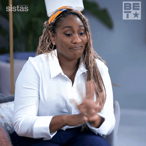 a woman in a white shirt is clapping her hands in front of a be tv logo