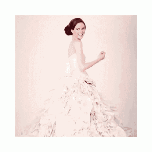a woman in a white wedding dress with ruffles on the skirt
