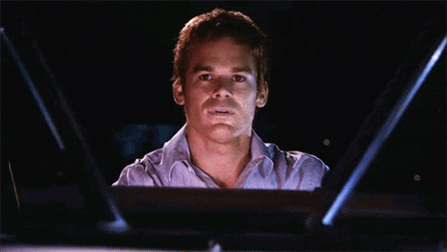 a man in a striped shirt is looking at a computer screen in the dark