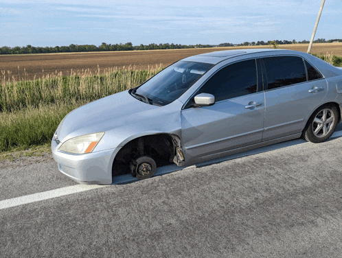 a silver car with a flat tire on the side of it