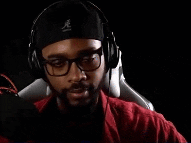 a man wearing headphones and a hat is sitting in a chair and playing a video game .