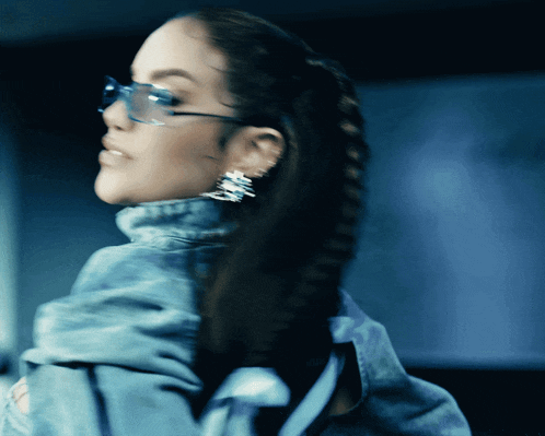 a woman wearing a denim jacket and sunglasses is looking over her shoulder
