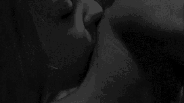 a black and white photo of a man and woman kissing each other .