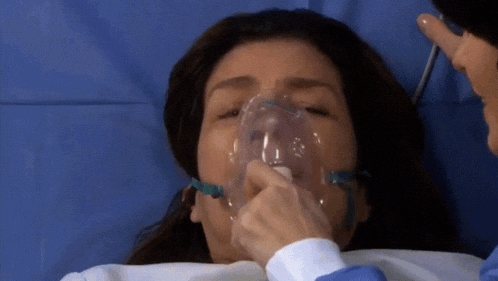 a woman with an oxygen mask on her face is laying in a hospital bed