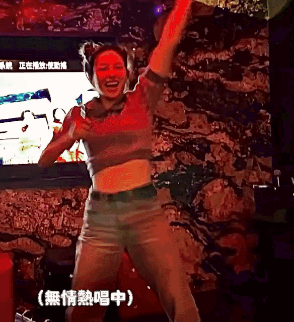 a woman is dancing in front of a tv screen with chinese characters on it