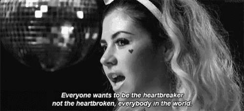 a black and white photo of a woman with hearts on her face and the words everyone wants to be the heartbreaker not the heartbroken .
