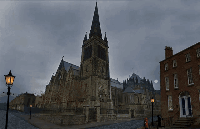 a church with a very tall steeple and a full moon in the background