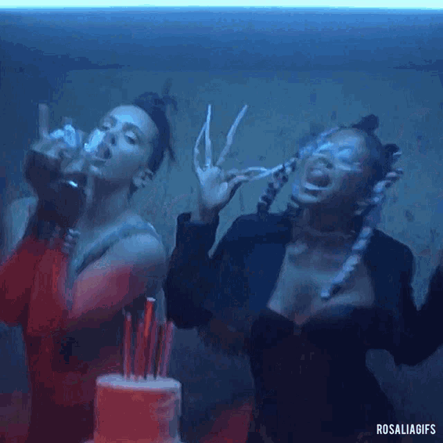 two women are dancing in front of a birthday cake with candles .