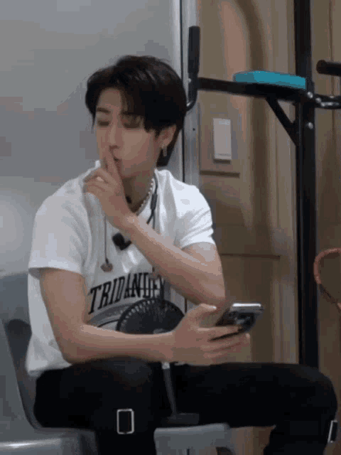 a man wearing a white shirt that says tridandy is smoking a cigarette
