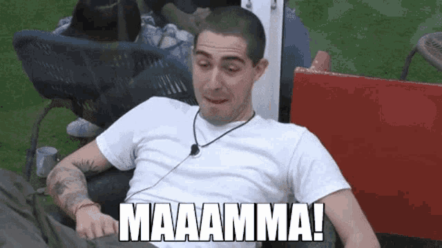 a man in a white shirt is sitting in a chair with the words maaaamma written above him .