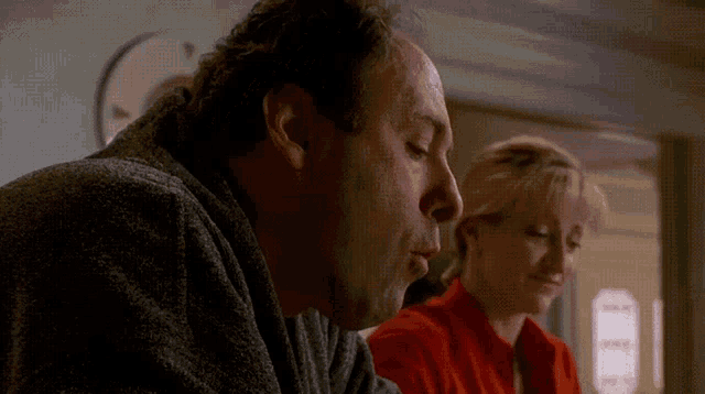 a man blows a kiss while a woman looks on