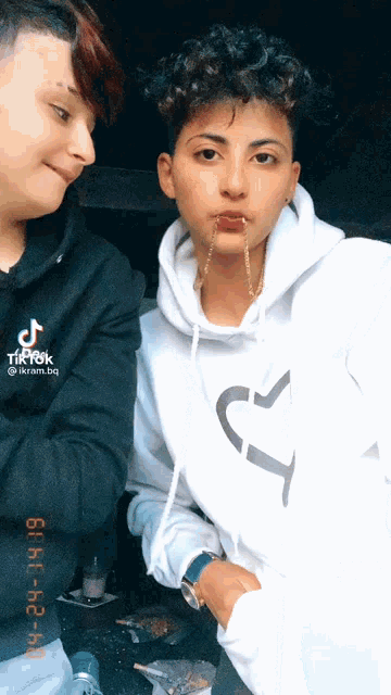 a woman with a piercing in her lip is wearing a white hoodie with a j on it