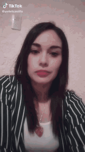a woman wearing a green and white striped jacket has a tiktok sticker on her shoulder