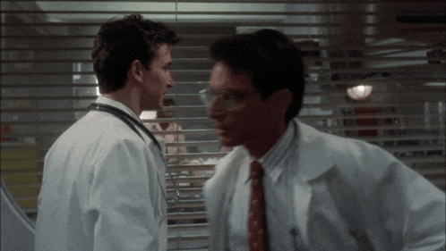 two men in white coats and ties are having a conversation