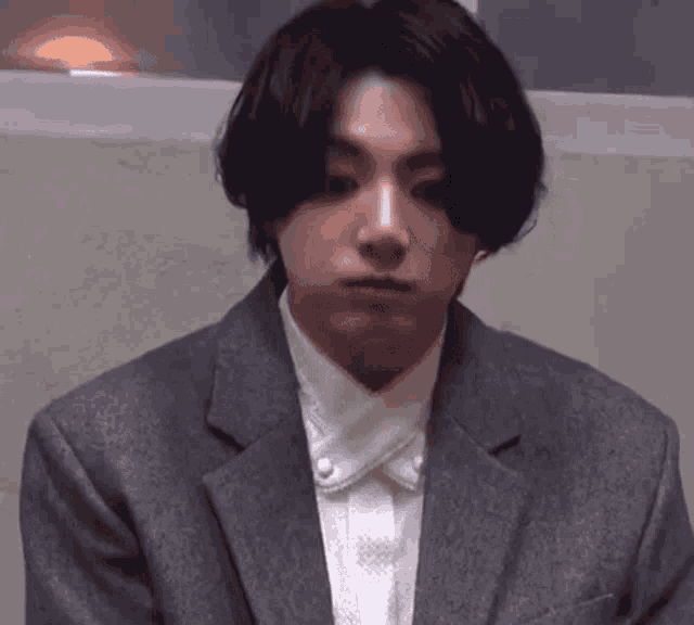a young man wearing a suit and a white shirt is looking at the camera .
