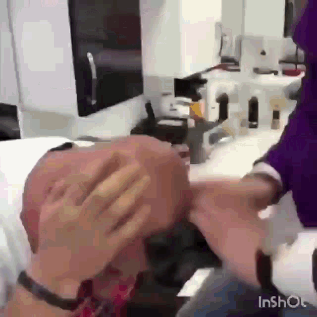 a man is getting his hair cut by a woman in a barber shop .