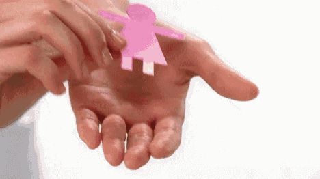 a person is holding a paper doll in their hand .