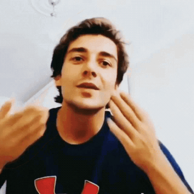 a young man wearing a blue shirt with a red u on it