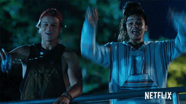 a man and a woman are standing next to each other with their arms in the air and the word netflix is on the bottom