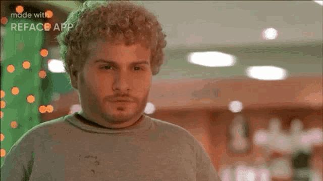 a man with curly hair and a beard is standing in a room with christmas lights in the background .