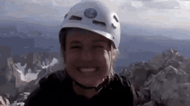 a woman wearing a helmet is smiling on the top of a mountain .