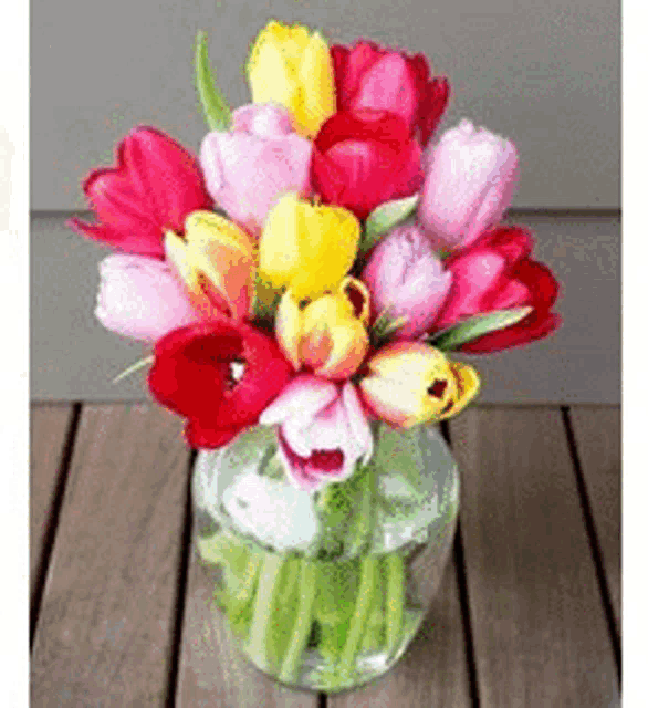 a vase filled with colorful flowers is on a wooden table .