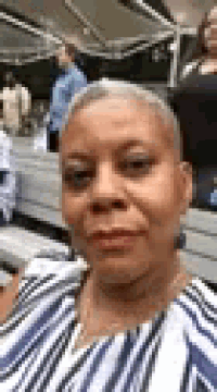 a woman in a striped shirt is taking a selfie while sitting on a bus .