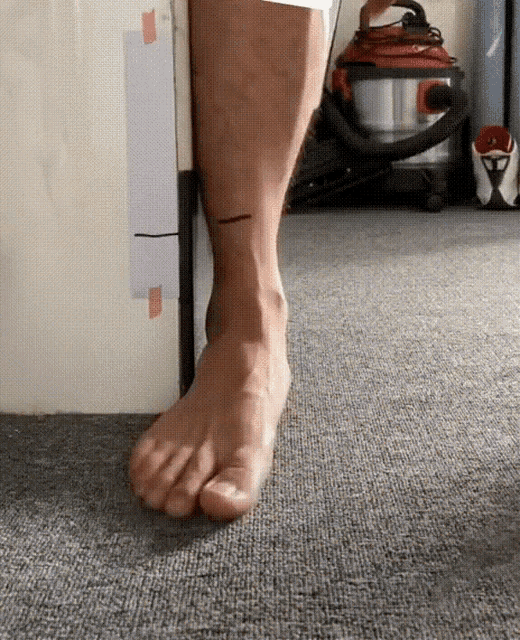 a person standing on a carpet with a vacuum cleaner behind them