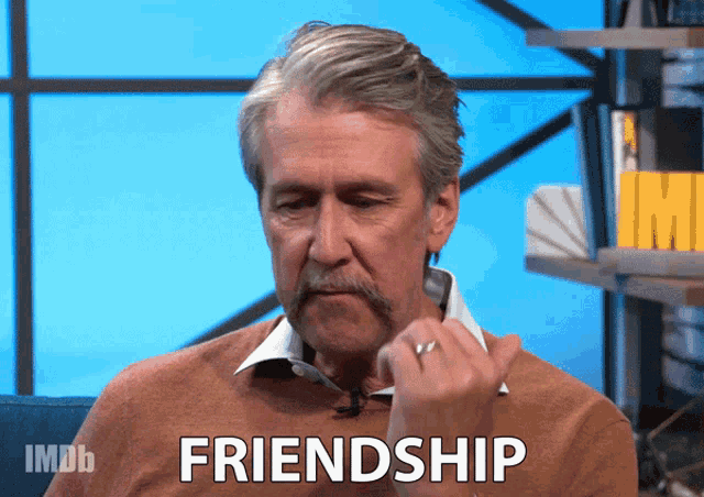 a man with a mustache and a ring on his finger says the word friendship