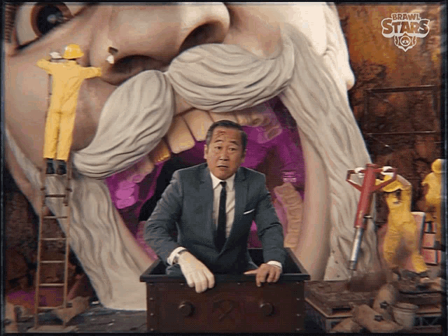 a man in a suit and tie is standing in front of a large statue with the words brawl stars now written on it
