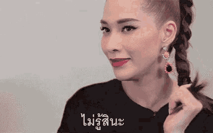 a woman wearing a braided ponytail and earrings is smiling and looking at the camera .