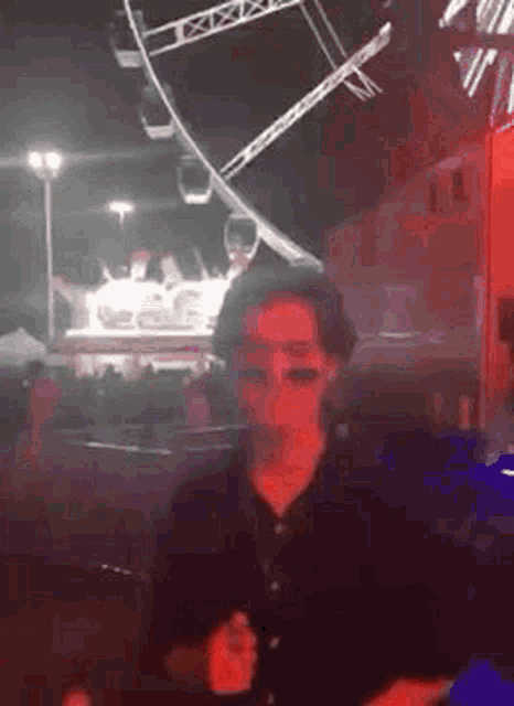 a man is dancing in front of a ferris wheel at a carnival .