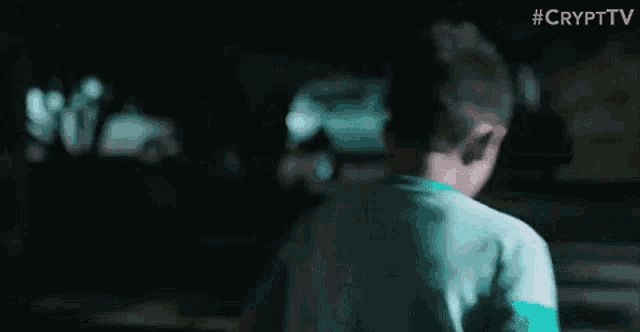 a young boy in a blue shirt is standing in a dark room .