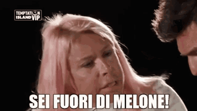 a woman with pink hair is standing next to a man and says sei fuori di melone !