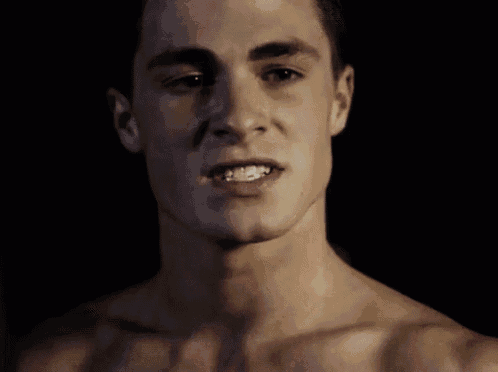 a close up of a shirtless man 's face with his mouth open .