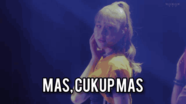 a woman in a yellow shirt has the words mas cukup mas on her face