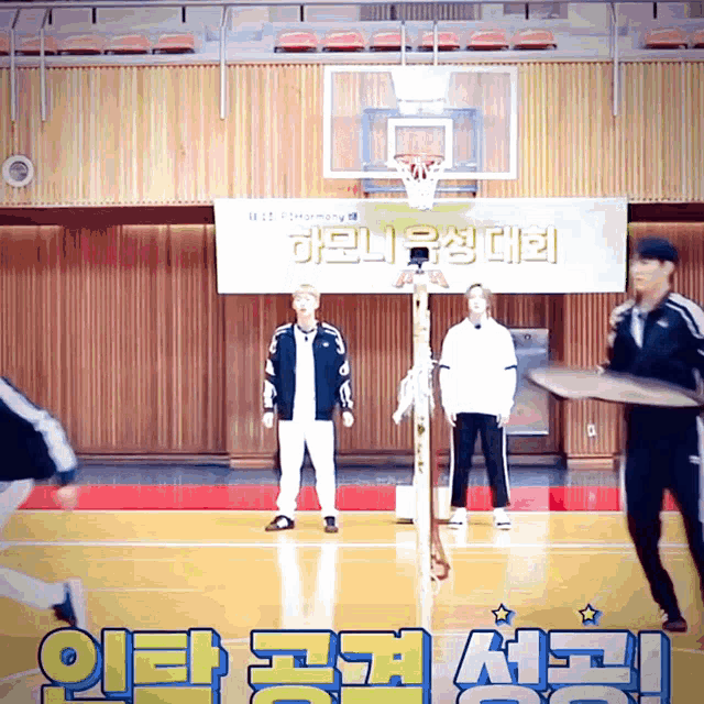 a group of people standing on a basketball court in front of a banner that says ' basketball ' on it