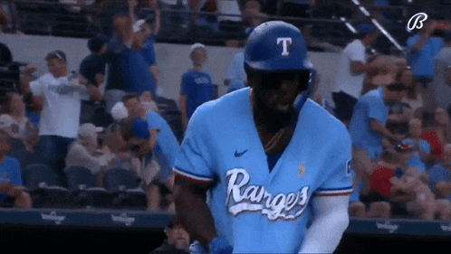 a baseball player wearing a blue jersey with the word rangers on it is standing on the field .