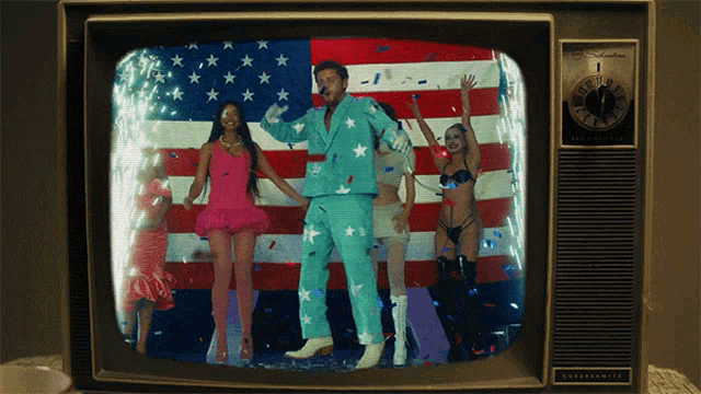 a television screen shows a man in a blue suit dancing in front of a flag