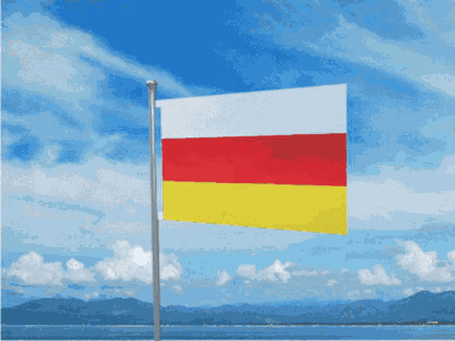 a red white and yellow flag flies in the wind