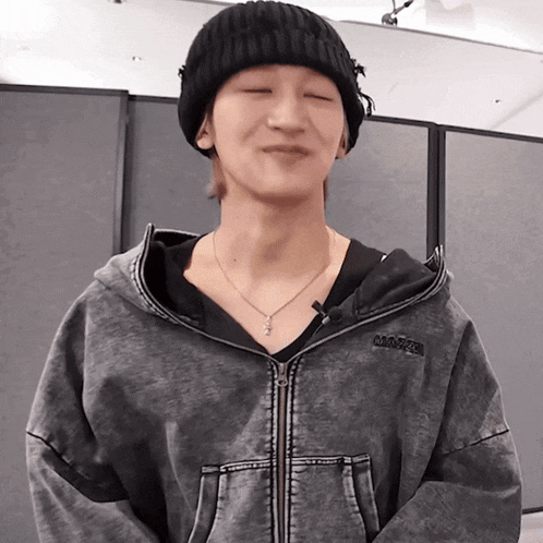 a man wearing a black beanie and a grey jacket with the word magic on the hood