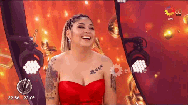 a woman in a red dress is laughing in front of a sign that says vivo