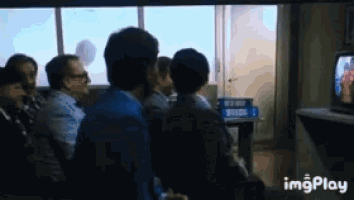 a group of people are sitting in front of a television with imgplay written in the corner
