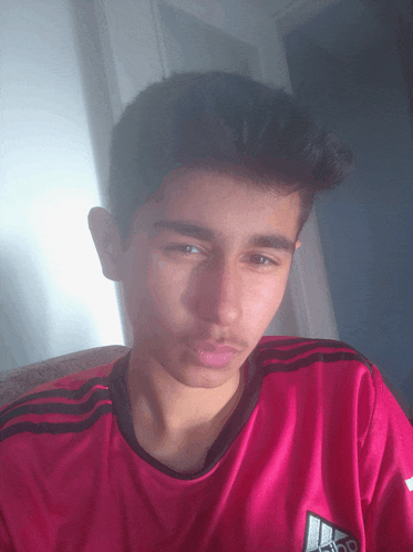 a young man wearing a pink adidas shirt