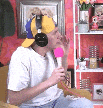 a man wearing headphones holds a pink microphone in his hand