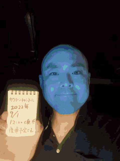 a man with blue paint on his face holds a notepad