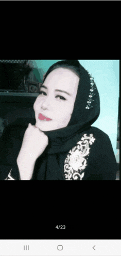 a woman wearing a black hijab with a floral embroidery on the front