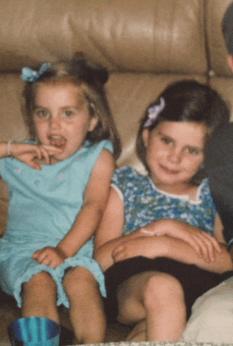 two little girls are sitting on a couch and one is eating